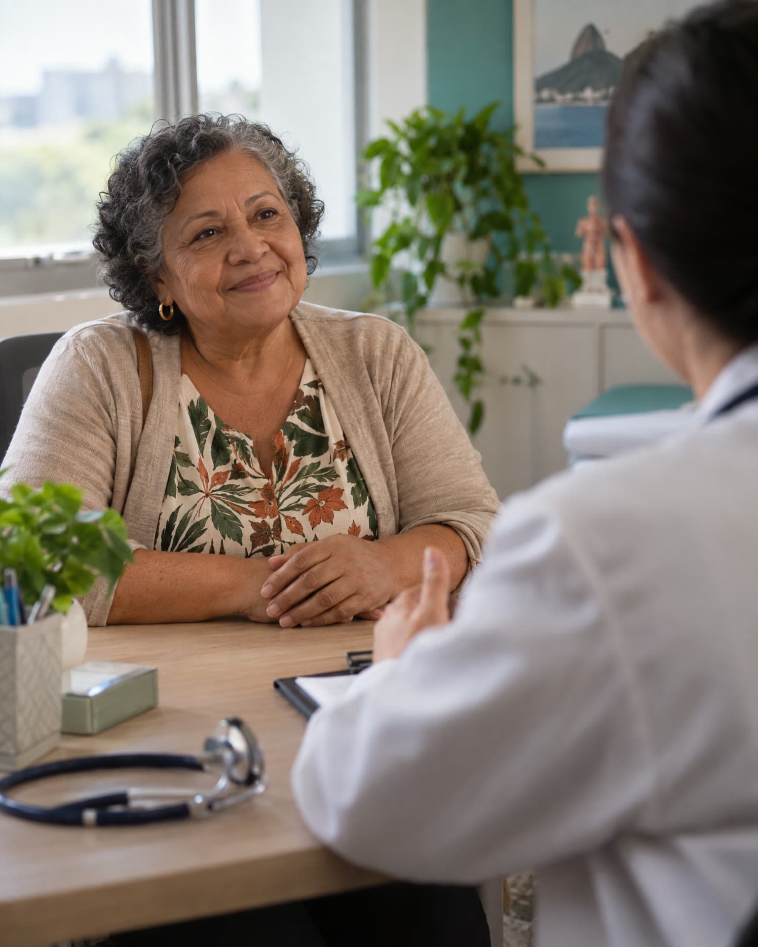 Paciente sorrindo durante consulta, médica de costas em primeiro plano